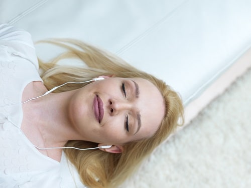 Relax in the rhythm of my music. Attractive young woman with earphones and smartphone sitting on sofa at home.